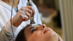 En kvinna som får behandling med microneedling - en lite dyna med massor med små nålar som gör hål på huden.
