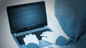 Cyberattacker och störning av kommunikationen är ett hot som påverkar alla. Person sitter och skriver på en dator.