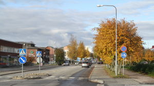 Bilar som kör på huvudgatan i Närpes. Träden vid sidan om vägen är i höstskrud.