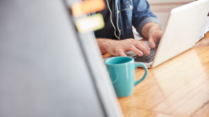 Häll upp en kopp kaffe eller te och börja på. Skriv vad som helst så lossnar det snart. En man som skriver på en laptop. Bredvid honom står en kaffekopp.