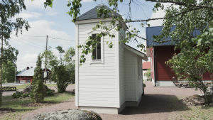 Kirkontornihan se siinä. Hyvin pienen, valkoiseksi maalatun puukirkon pääty. Kirkko sijaitsee pihassa jossa useita punaisia rakennuksia.