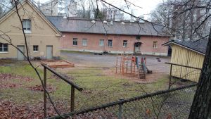Gadolins laboratorium idag som daghem med utbyggnader från 1920. Fotograferat från Vårdbergsparken gårdshelhet med ett rött stenhus, ett gult rappat hus och ett hus av trä med lekpark för barn i mitten