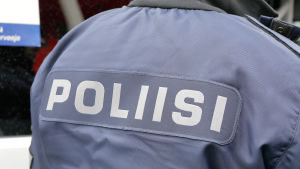 Polis, fotograferad bakifrån så att texten "poliisi" syns på ryggen.