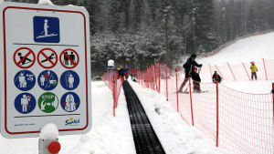 Det finns tydliga anvisningar för hur man ska bete sig på rullbandet. I förgrunden en skylt som ebrättar hur man ska bete sig i mattliften som syns i bakgrunden.