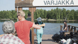Salmen voisi ylittää myös veneellä. Mutta kapulalossi tuntuu sopivan ainutlaatuiselta ja verkkaiselta tavalta lähestyä määränpäätä, sillä samalla tavoin saareen kulkivat sahan työntekijät aikoinaan. Mieli valmistautuu tutustumaan autiosaareen. Kuva kapulalossilta kohti menosuuntaa, Varjakanniemestä kohti vastarannalla näkyvää Varjakansaarta, lossin yläosassa kyltti jossa lukee Varjakka.