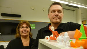 Carina Storhannus och Kaj Ekroos ansvarar för projektet. En kvinna och en man står vid olika figurer gjorda med en 3D-printer.