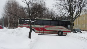 Wikströms bussar kör många turer mellan Bromarv och Ekenäs. Staden betalar en del av dem. Arkivbild. En grå och röd buss åker nerför en snöig gata.