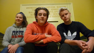 Jenna Ingves, Mathias Thijssen och Zacharias Hagback. Tre ungdomar sitter på en trappa inne i Kristinestads gymnasium.