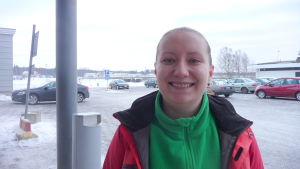 Jasmin Hietanen. En leende kvinna med en röd jacka ovanpå en grön fleece-tröja.