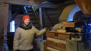 Anna Alm driver också numera Svartå kvarn. Anna Alm står vid en maskin som skalar spannmål.
