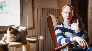Vaikka lämpömittarin mukaan asia olisi toisin päin, täällä kylmyys ei mene luihin ja ytimiin samalla tavoin kuin entisessä kotimaassa, Piers perustelee. Ja talot ovat mukavan lämpimiä. Oopperalaulaja Piers Bray istuu keinutuolissa olkapäällään burmankissa