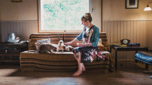 Ensivaikutelmat kotitalosta toivat Marielle mieleen hänen mummolansa. En kvinna sitter i en soffa med några katter.