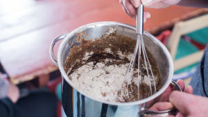 Mjöl, malt, vatten och en gnutta salt rörs om. Mjöl, malt och vatten blandas i en kastrull.