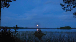 Solnedgång över Sumiaisjärvi. Sinertävä tyyni järvenselkä, auringonlasku.