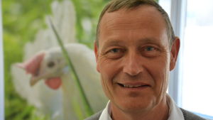 Janne Torikka, verkställande direktör för Munax. janne torikka ler mot kameran och har en bild på ett höns i bakgrunden