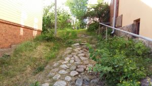 En innergård i centrum av Åbo. stenig backe upp mot lummig trädgård vid gult hus