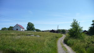 En skärgårdsby med en väg genom en äng och en vit kyrka i bakgrunden