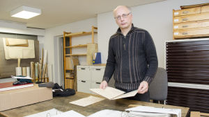 Jan Ehnvall vet mycket om Pirilö-Karl. En man står i ett rum som är fyllt med arkiveringslådor och gamla papper. Han håller i ett gammalt handskrivet dokument.
