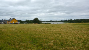 Reatomterna ligger precis intill Kyrkträsket. Ett landskap som består mest av gräs och vyn mot en sjö. Till vänster några hus.