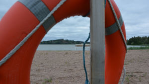 Strax intill bostadsområdet ligger en simstrand. Strand som synns genom räddningsring.