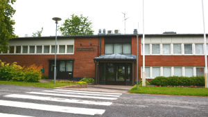 Kommunhuset i Mörskom. Ett lågt rött tegelhus vid en övergångsväg. På väggen står kunnanvirasto, kommunkansliet.