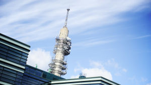 Blåvit himmer och i förgrunden en byggnad bakom vilken Yles tv-torn syns.