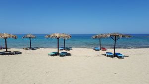 Kreetalainen uimaranta, jossa aurinkotuoleja ja -varjoja
