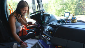 Arbetet är mångsidigt och det är roligt att göra allt själv, säger Isabelle Rio. Kvinna sitter i förarhytten vid ratten och talar i telefon medan hon antecknar i ett block.