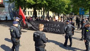 Polisen omringar demonstranterna på torget vid nutidsmuseet Kiasma. En grupp demonstranter omringas av polisen på ett stentorg.