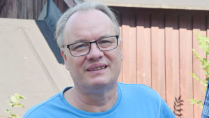 Lennart Biström jagar i skärgårdsmiljö. En man i blå t-skjorta ler mot kameran. Han har glasögon och kort hår.