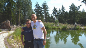 Ben Henriksson och Ilkka Vainio. I bakgrunden syns fiskdammen där kunder kan meta lax. Två män står framför en liten damm.