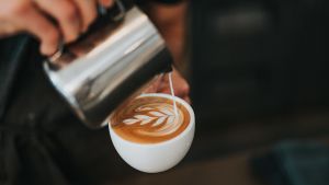 Emilia dricker kaffe med mjölk för sin röst. maitovaahtoa kaadetaan cappuccinon päälle