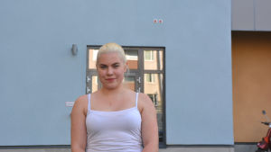 Ansa Kurki ville flytta närmare skolan. Hon är nöjd med sitt nya hem. En ung kvinna står framför en blå yttervägg.