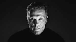Jari Sarasvuo. Sarasvuo katsoo kameraan ja hymyilee vienosti.
