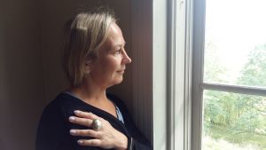 Tuija Ramsay tänker på sköldpaddor. Tuija Ramsay står vid ett fönster med en stor ring på fingret.
