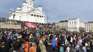 Demonstranter som deltar i klimatmarschen samlas framför Helsingfors Domkyrka.