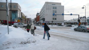 Fredrick von Schoultz kastar fram idén om att man i fortsättningen kunde ploga lättrafiklederna före gatorna. Flera personer går längs en gata i centrum av Borgå. Marken är täckt av snö.