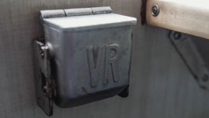 Metallinen, vanhan junavaunun seinään kiinnitetty tuhkakuppi tekstillä "VR". 