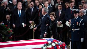 George W Bush, med fru Laura, går förbi sin fars kista. George Bush, med fru Laura, går förbi sin fars kista, draperad i USAs flagga.