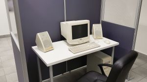 Nayab Ikrams konstverk har inspirerats av något hon kallar för office noir, som handlar om att fånga den kusliga känslan i ett tomt kontorslandskap. Bild på Nayab Ikrams konstverk som är ett kontorslandskap med tillhörande kontorsmöbler samt en stor dator av äldre modell.