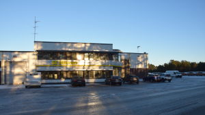 I början av 2018 expanderade SE Mäkinen till den här vita byggnaden på frihamnsområdet. SE Mäkinen arbetar med PDI-granskning och montering av tilläggsutrustning i båda byggnaderna. Logistikföretaget SE Mäkinens byggnad i frihamnen i Hangö.