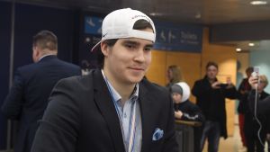 Aarne Talvitie var först ut av spelarna i ankomsthallen. Aarne Talvitie med medaljen runt halsen