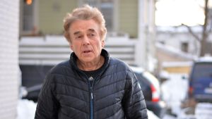 Carl-Gustav Måsa är förvånad över beslutet om flytt. Man i svart jacka utomhus ser uppåt medan har pratar. I bakgrunden en gul byggnad och snöbeklätt träd.