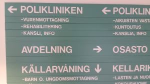 Gröna skyltar med som visar vart man ska gå för att komma till polikliniken, avdelning eller källarvåning på en psykiatrsik mottagning-.