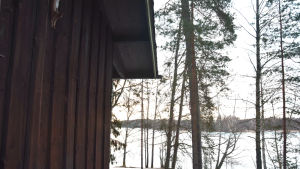 Stugan ska fortsätta vara utan vatten och el. Hörnet av en stuga och i bakgrunden ett vinterlandskap.