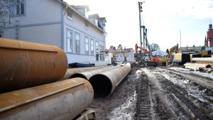 Många pålar slås i marken för att stöda broarna. Flera pålar ligger på rad nära bygget.