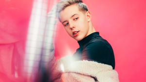 Tuure Boeliuksella on Youtubessa yli 150 tuhatta tilaajaa. Tuure Boelius katsoo pinkun taustan edessä vasempaan alaviistoon, kuva rajattu rinnasta alaspäin.