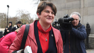 Arlene Foster Kvinna ler mot kameran och blir filmad av en man i bakgrunden