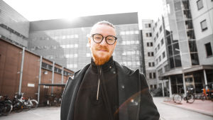 Kun Jurek uupuu, hän sulkee puhelimensa ja pelaa kolme päivää pleikkaria. Jurek Reunamäki seisoo toimistorakennuksen edessä, taustalla polkupyöräparkki. Hymyilee tummissa vaatteissaan ja silmälaseissaan, aurinko heijastuu takaa. Kuva rajattu kyynärpäistä alaspäin.