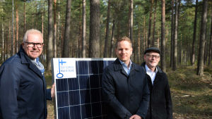 Stadsdirektör Ragnar Lundqvist, Energibolagets vd Frank Hoverfelt och Henrik Ekblom, vd för Karis Telefon i skogen där solkraftverket byggs. Tre män står vid en solpanel.